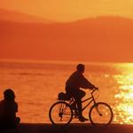 Bike Rider And Couple Relaxing. Spanish Banks Sunset With View Of English Bay & West Vancouver. Vancouver BC.