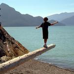 Boy Walking On Log With View Across Howe Sound. Porteau Cove BC.