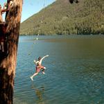 Two Boys Using Rope Swing Jumping Into Lake. Paul Lake Near Kamloops, Caribou Region BC.